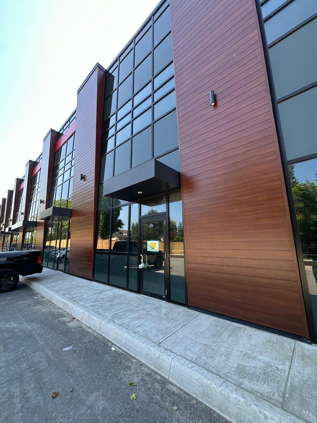 Commercial office facade with wood-look cladding and black curtain wall
